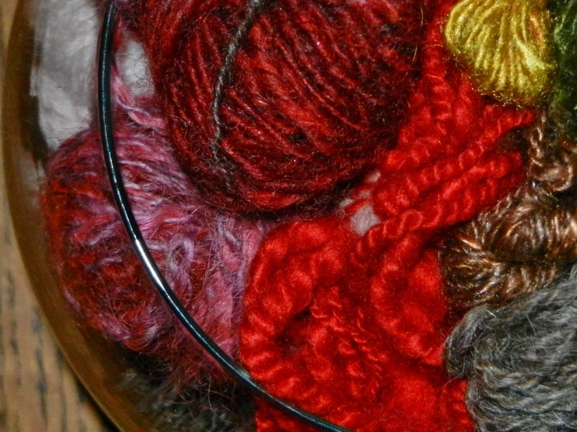 Close up of small red, pink, yellow, green balls of handspun yarns in a bowl.
